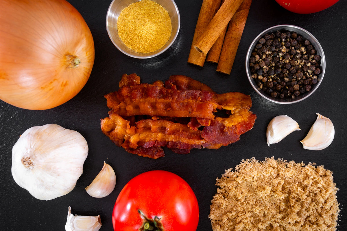bourbon glaze uncured bacon jerky surrounded by ingredients on a dark slate background