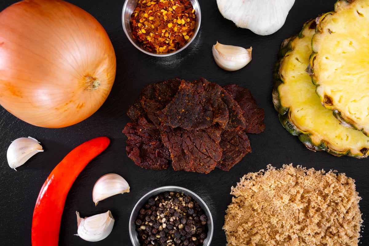joe cocky teriyaki premium beef jerky surrounded by ingredients on a dark slate background