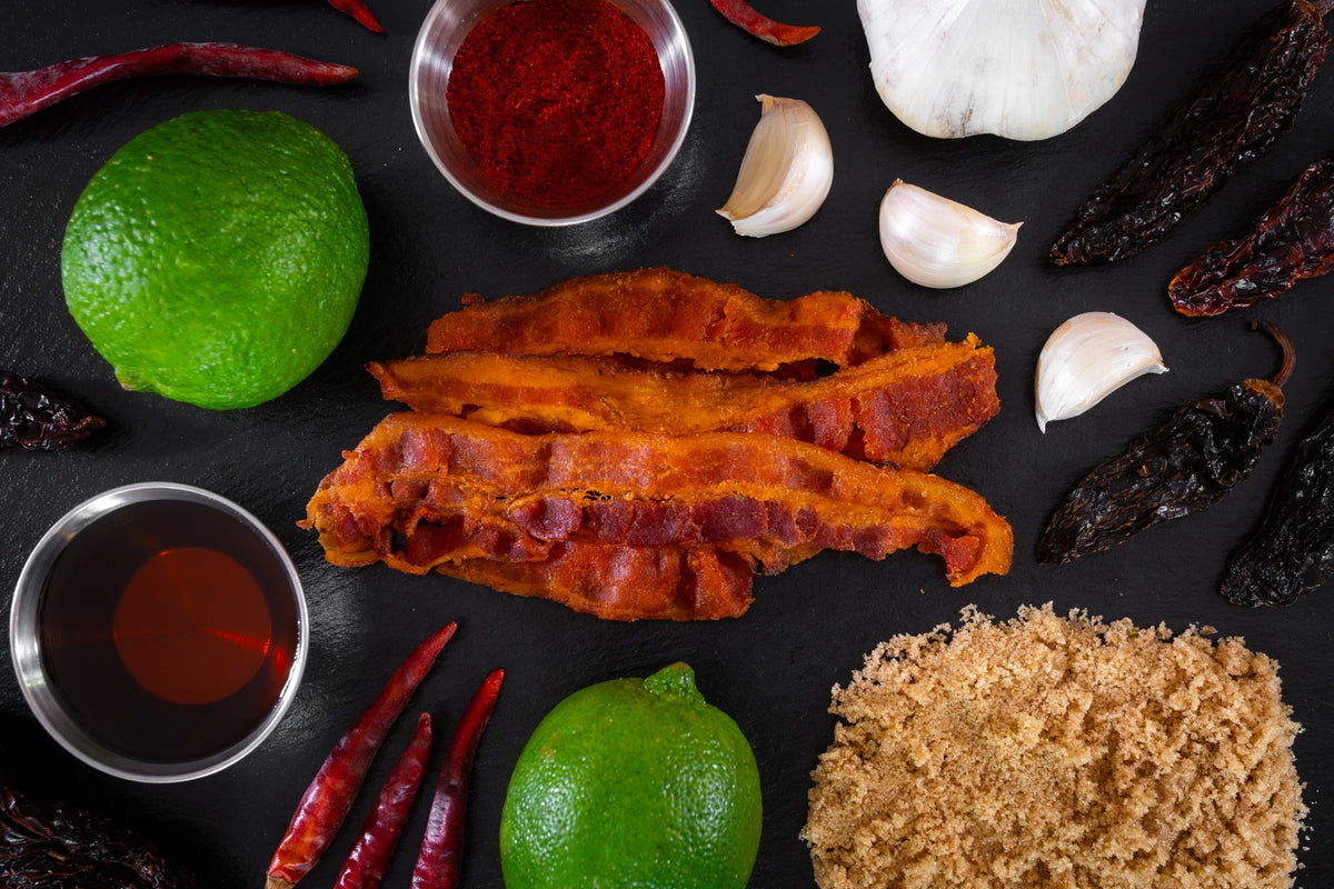 sizzlin maple uncured bacon jerky surrounded by ingredients on a dark slate background